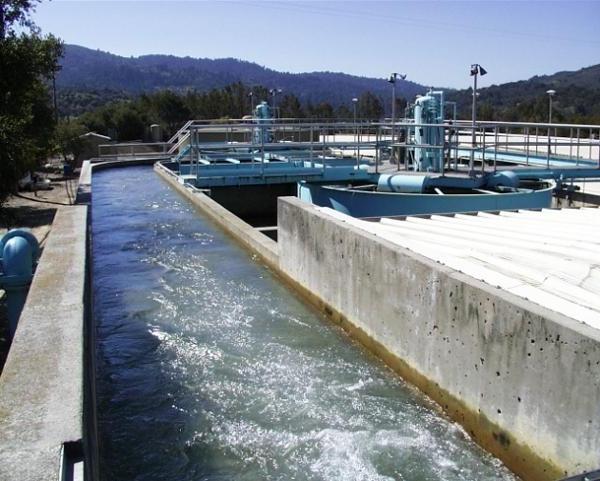 Water rushing along an outdoor concrete channel at a water treatment plant